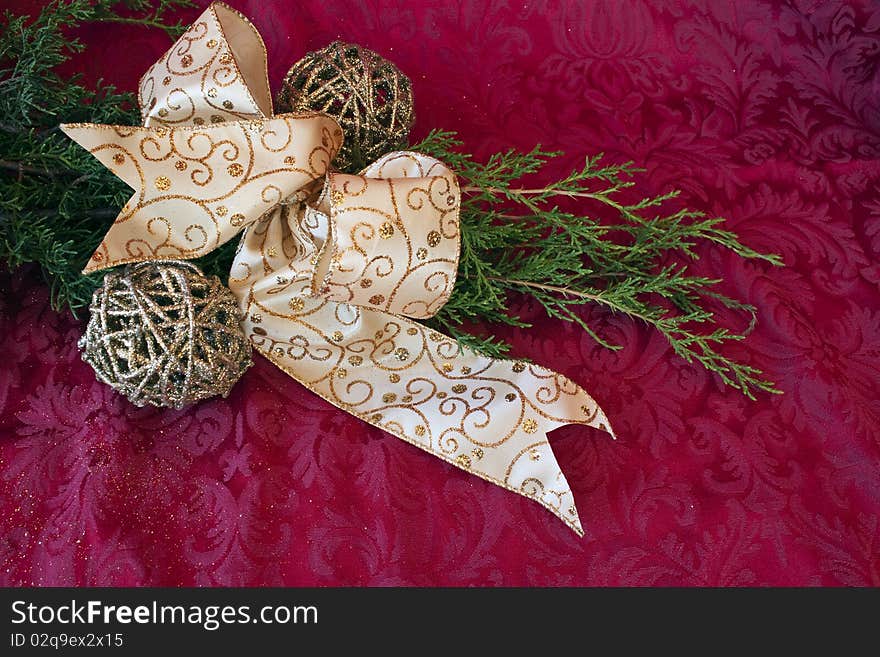 Greenery with ribbon and glittery balls on a red brocade