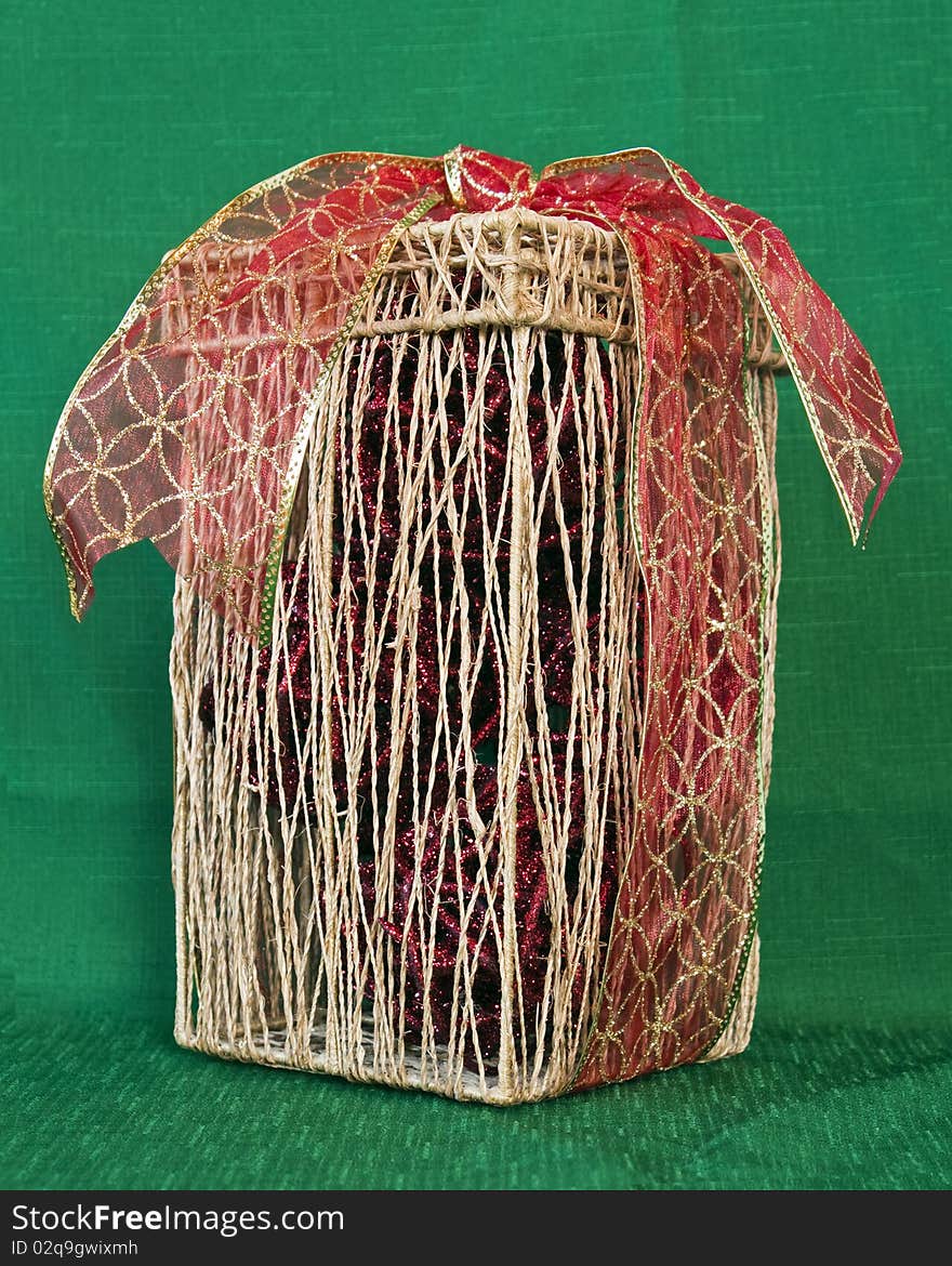 Straw Decorative box with red and gold ribbon on a green textile