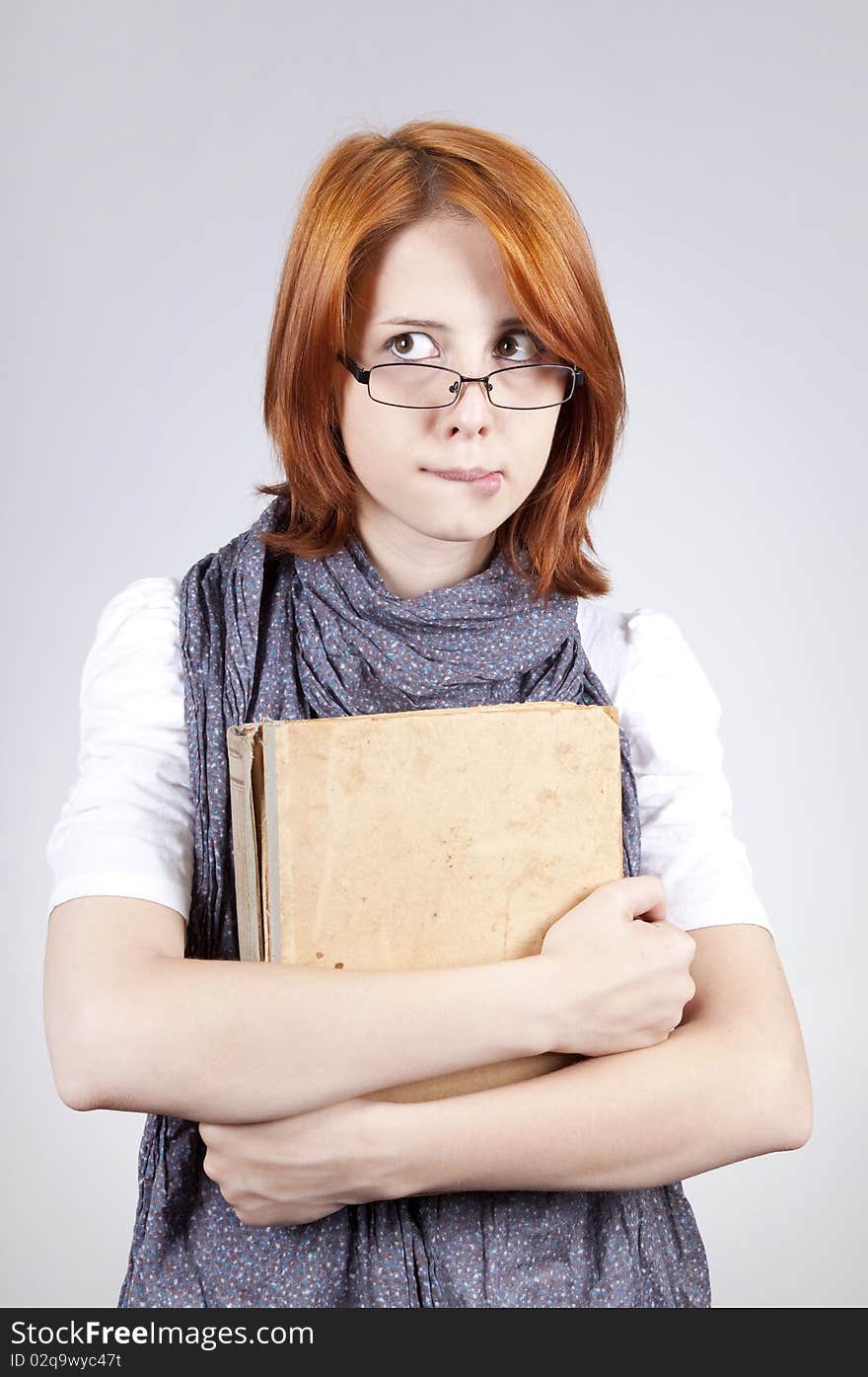 Doubting fashion girl in glasses with old book