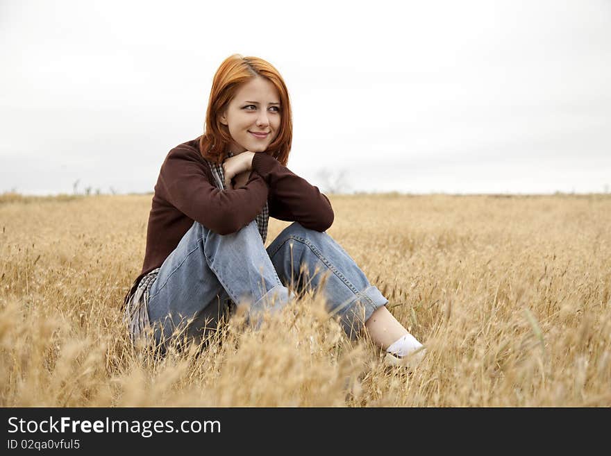 Beautiful Red-haired Girl At Yellow Autumn Grass.