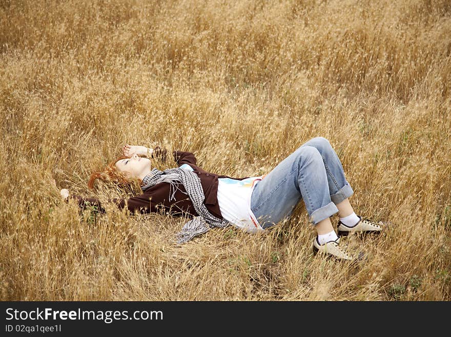 Young beautiful girl lying at yellow autumn field.