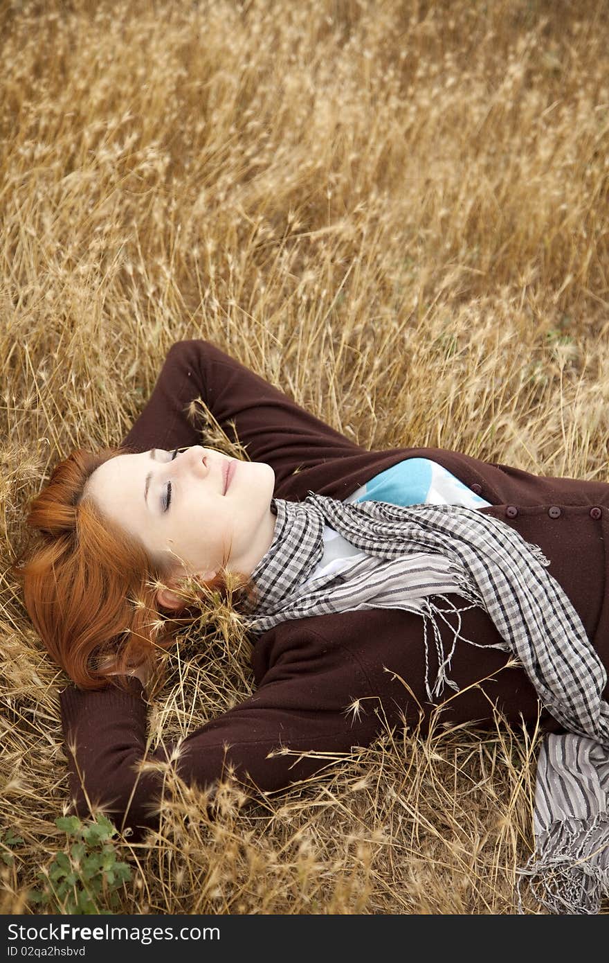 Young beautiful girl lying at yellow autumn field.