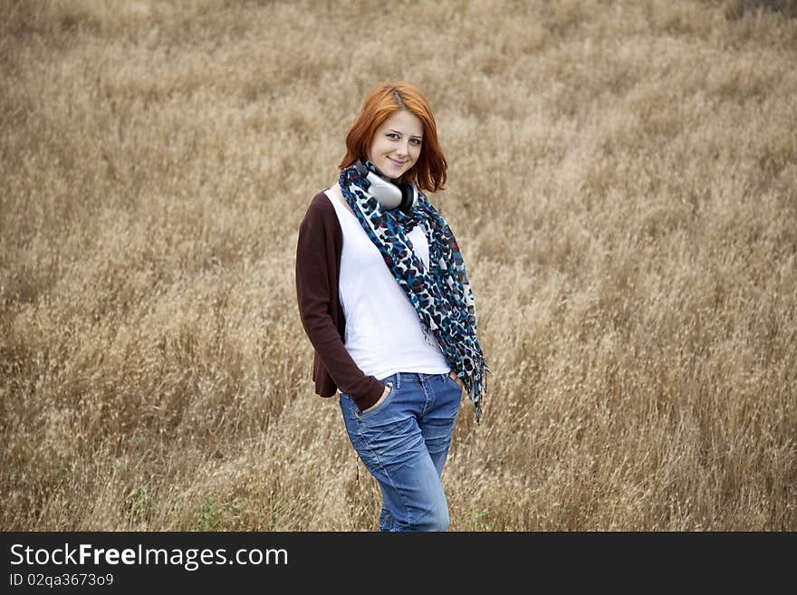 Young  smiling fashion with headphones at field. Outdoor photo.