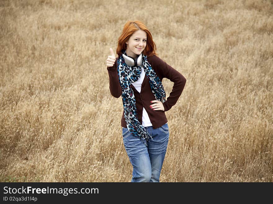 Young  smiling fashion with headphones at field. Outdoor photo.