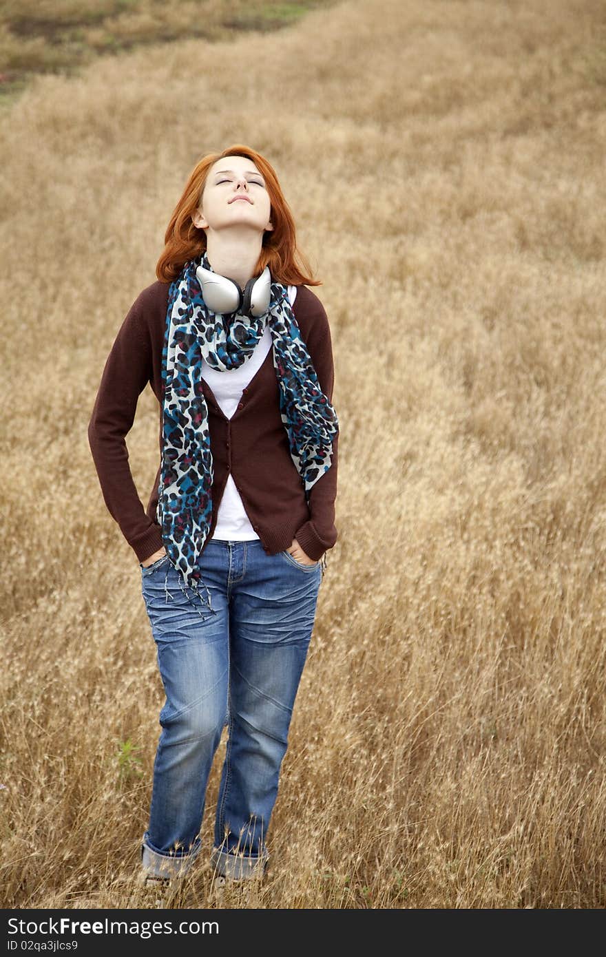 Young girl with headphones at field. Outdoor photo.