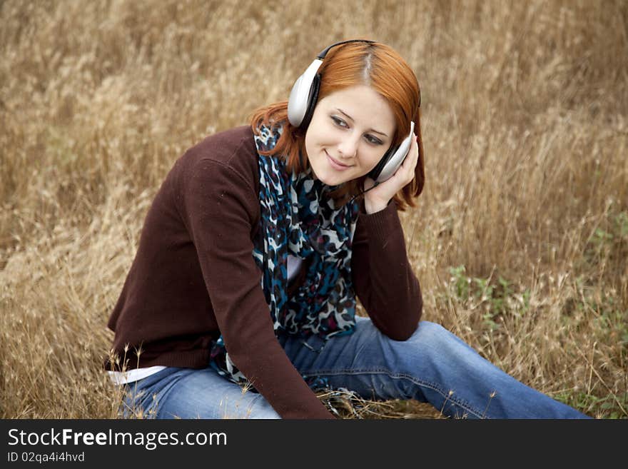 Young girl with headphones at field. Outdoor photo.