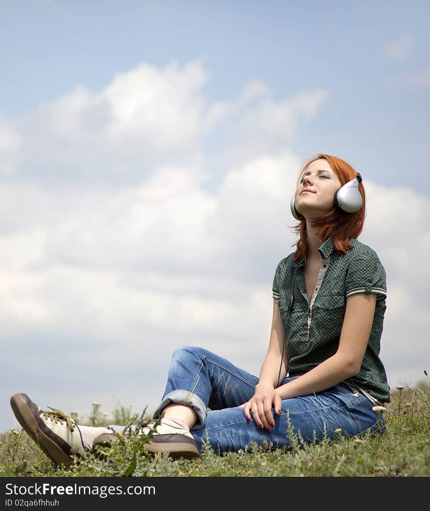 Young smiling girl with headphones sitting at green grasss. Young smiling girl with headphones sitting at green grasss.