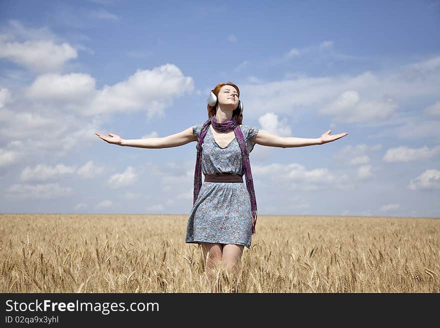 Young  smiling girl with headphones at field. Outdoor photo.