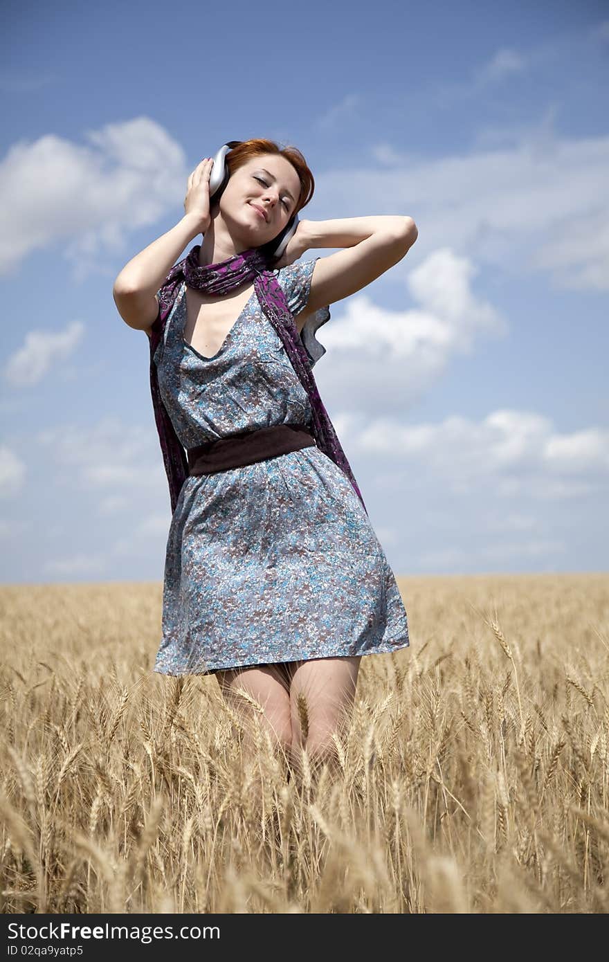 Young  smiling girl with headphones at field.