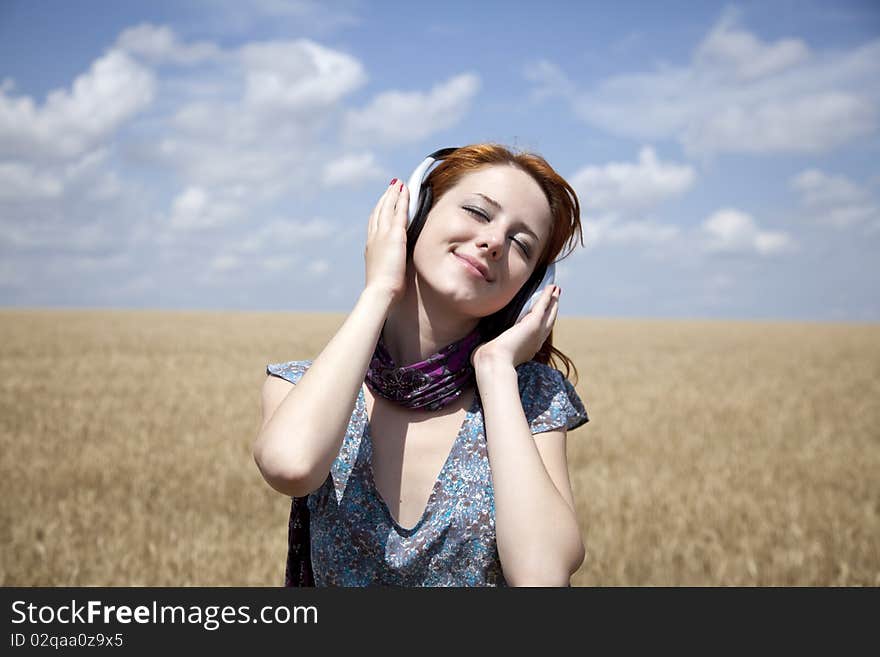 Young  smiling girl with headphones at field.