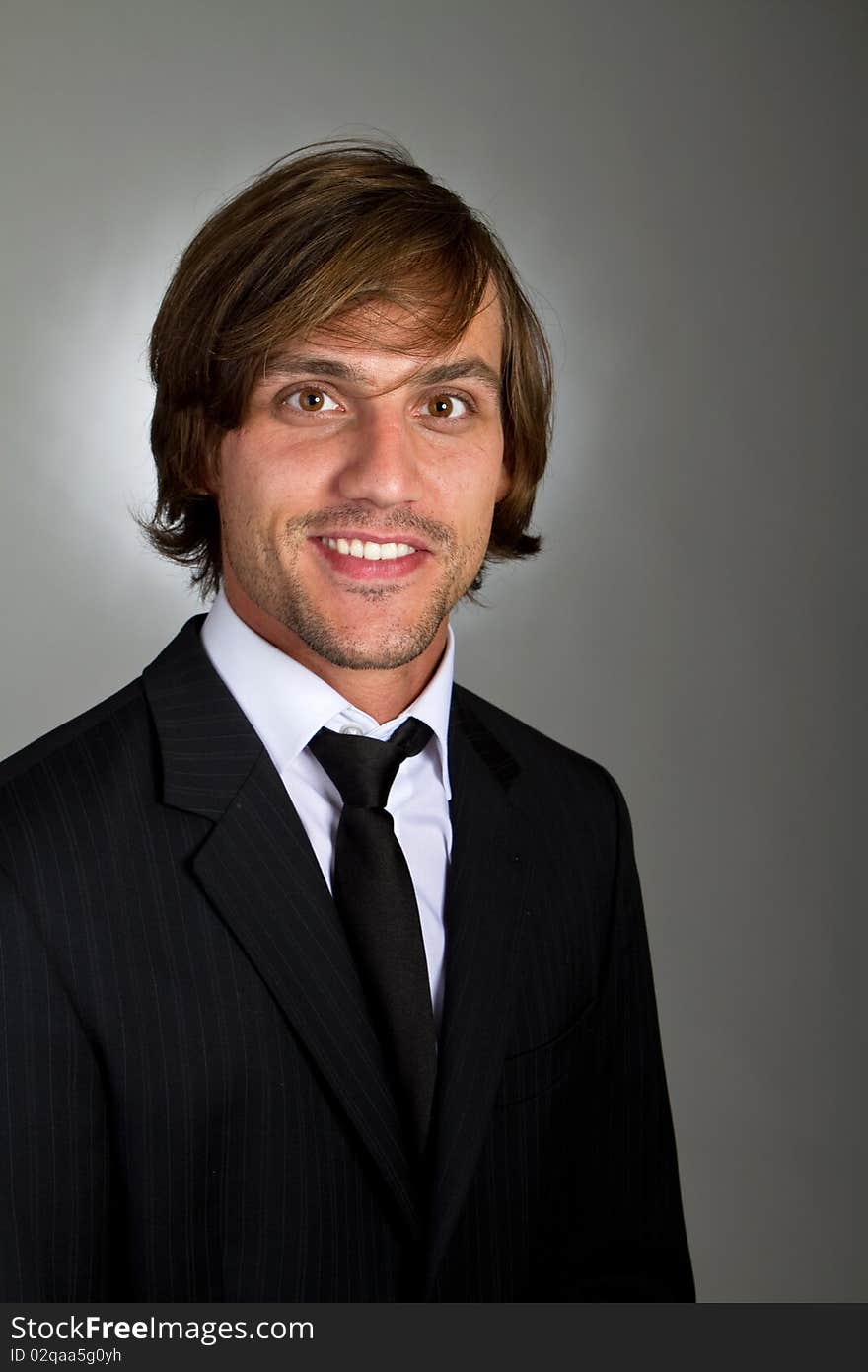 Young fresh confident businessman with longer hair over a greyish background. Young fresh confident businessman with longer hair over a greyish background.