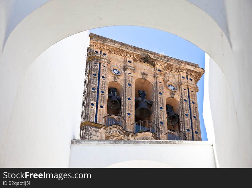 Santa Maria church bell tower framed by a white arch in Arcos de la Frontera, Cadiz - Spain