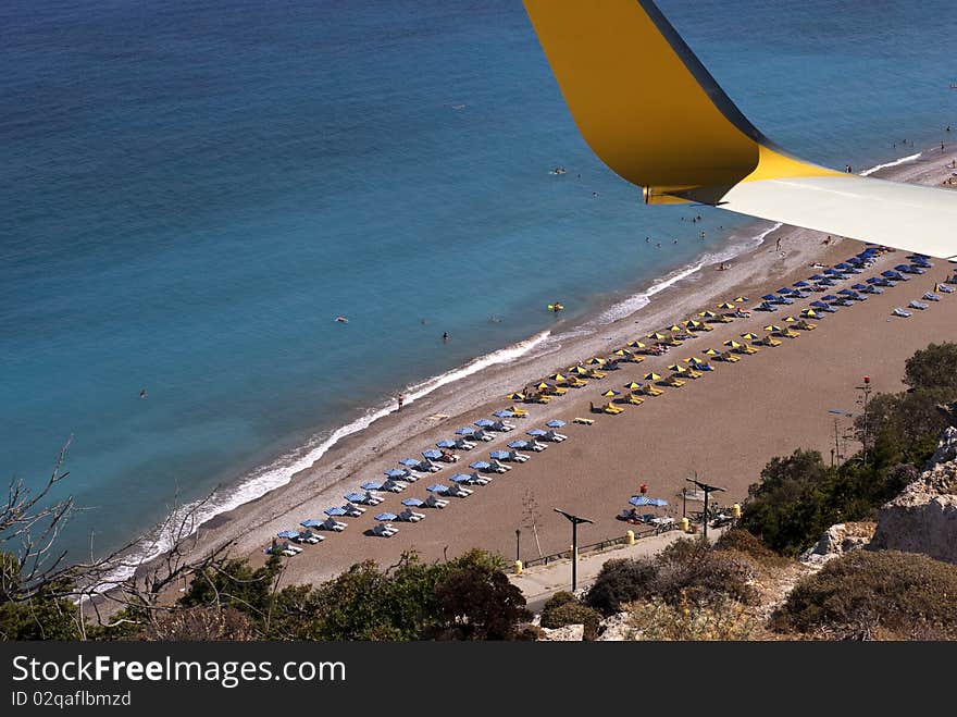 Airplane wing and beach in summer with parasols and beach chairs close to the sea. Airplane wing and beach in summer with parasols and beach chairs close to the sea.