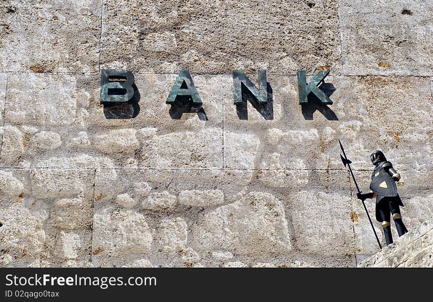 Bank sign on old wall protected by knight in armor. Bank sign on old wall protected by knight in armor.