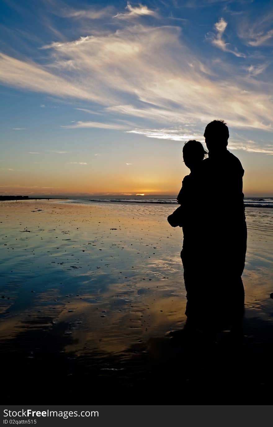 Young couple holding each other on a romantic beach at twilight