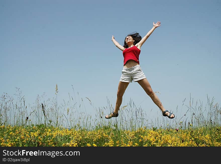 Beautiful young woman jumping in a meadow with yellow flowers