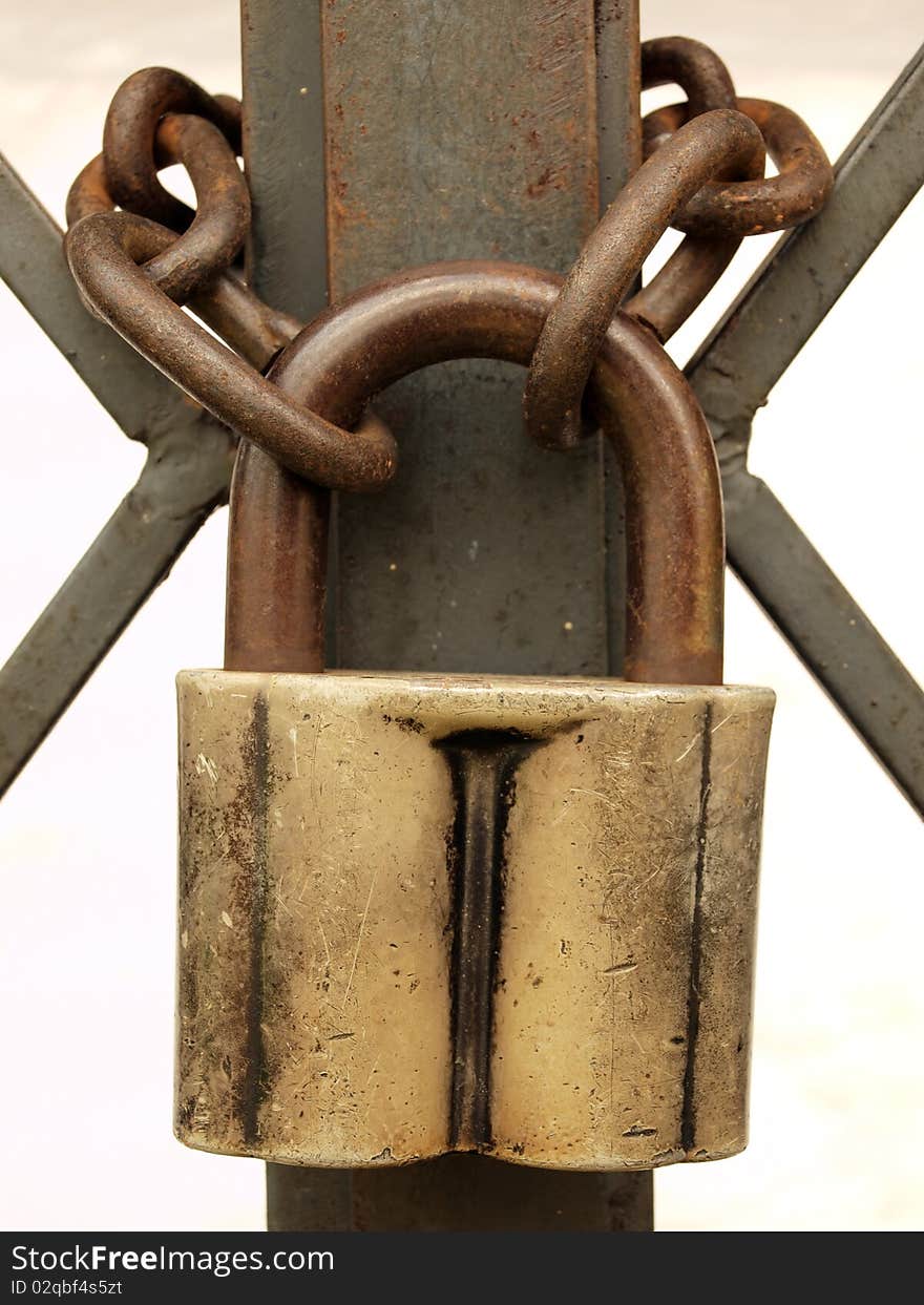 The old padlock and rusty chain on a metal lattice.