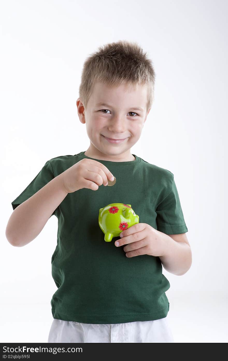 Little boy depositing money in his piggy bank.