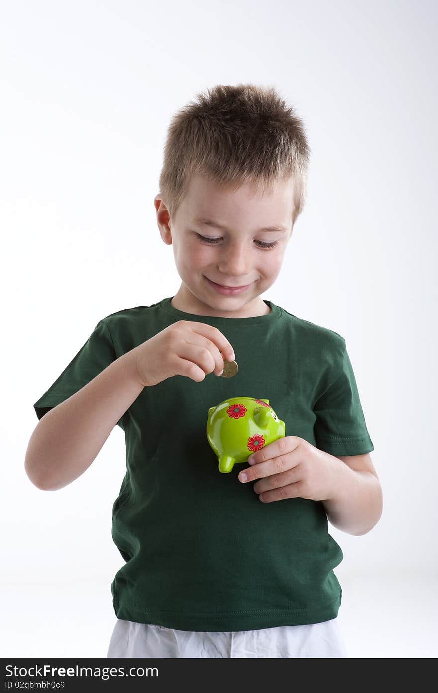 Little boy depositing money in his piggy bank.