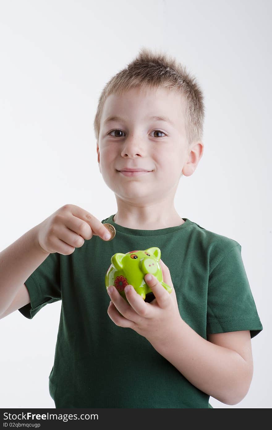 Little boy depositing money in his piggy bank. Concept: my future