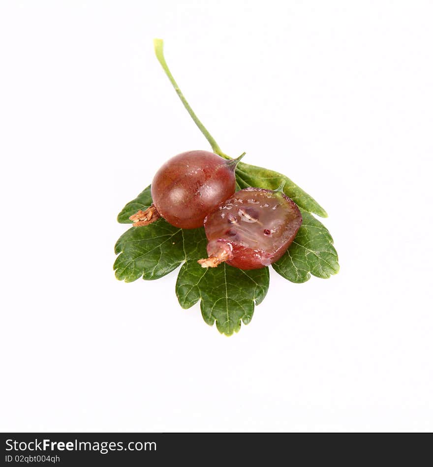 Red gooseberries, one cut in half, on a leaf on white background