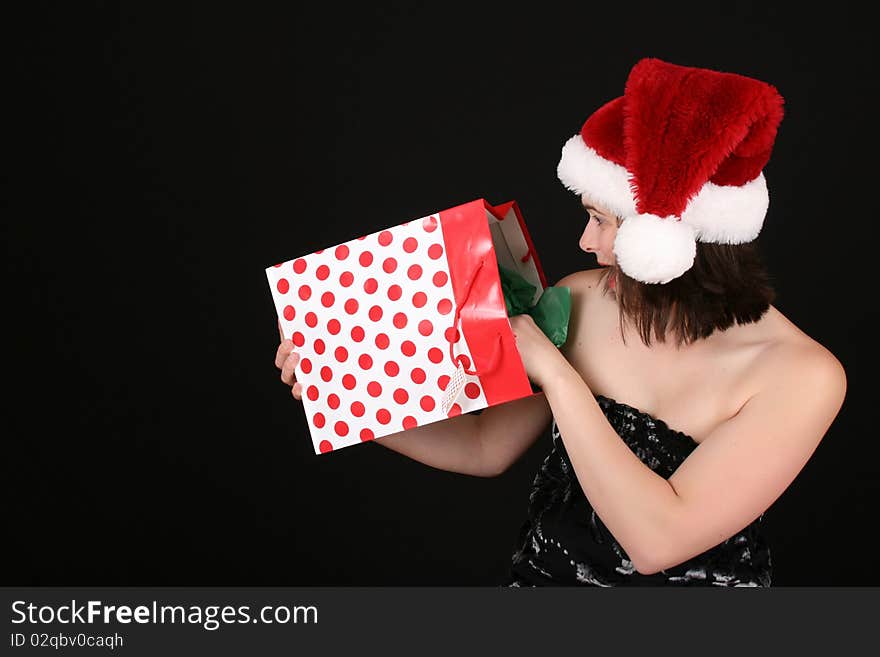 Beautiful brunette female wearing a christmas hat surprized at her gift. Beautiful brunette female wearing a christmas hat surprized at her gift