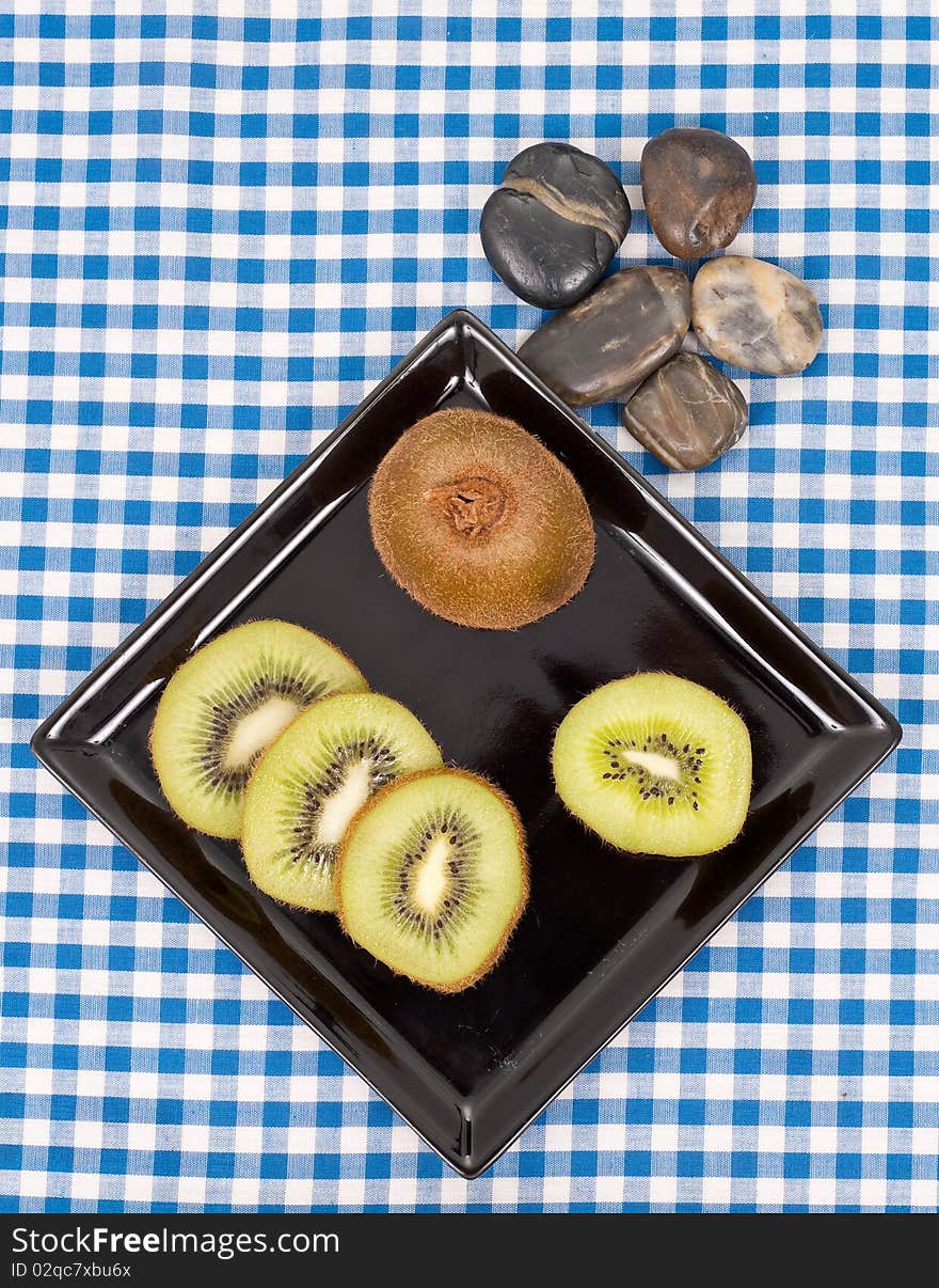 Sliced Kiwi on Black Plate with Rock Decorative. Sliced Kiwi on Black Plate with Rock Decorative