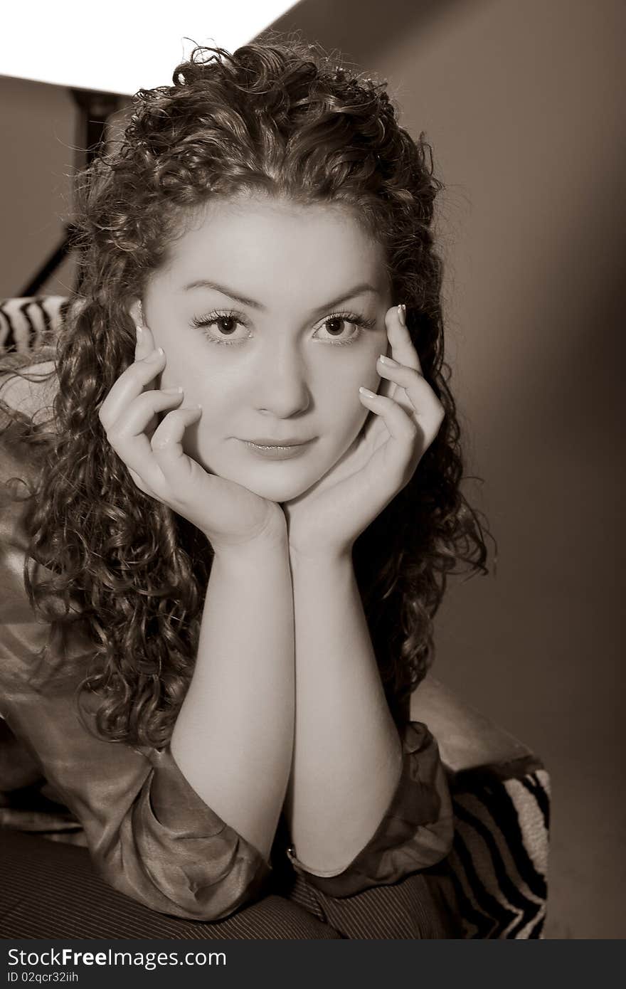 Young and tired caucasian girl in studio sitting in chair with hands support and staring.picture made with color correction. Young and tired caucasian girl in studio sitting in chair with hands support and staring.picture made with color correction