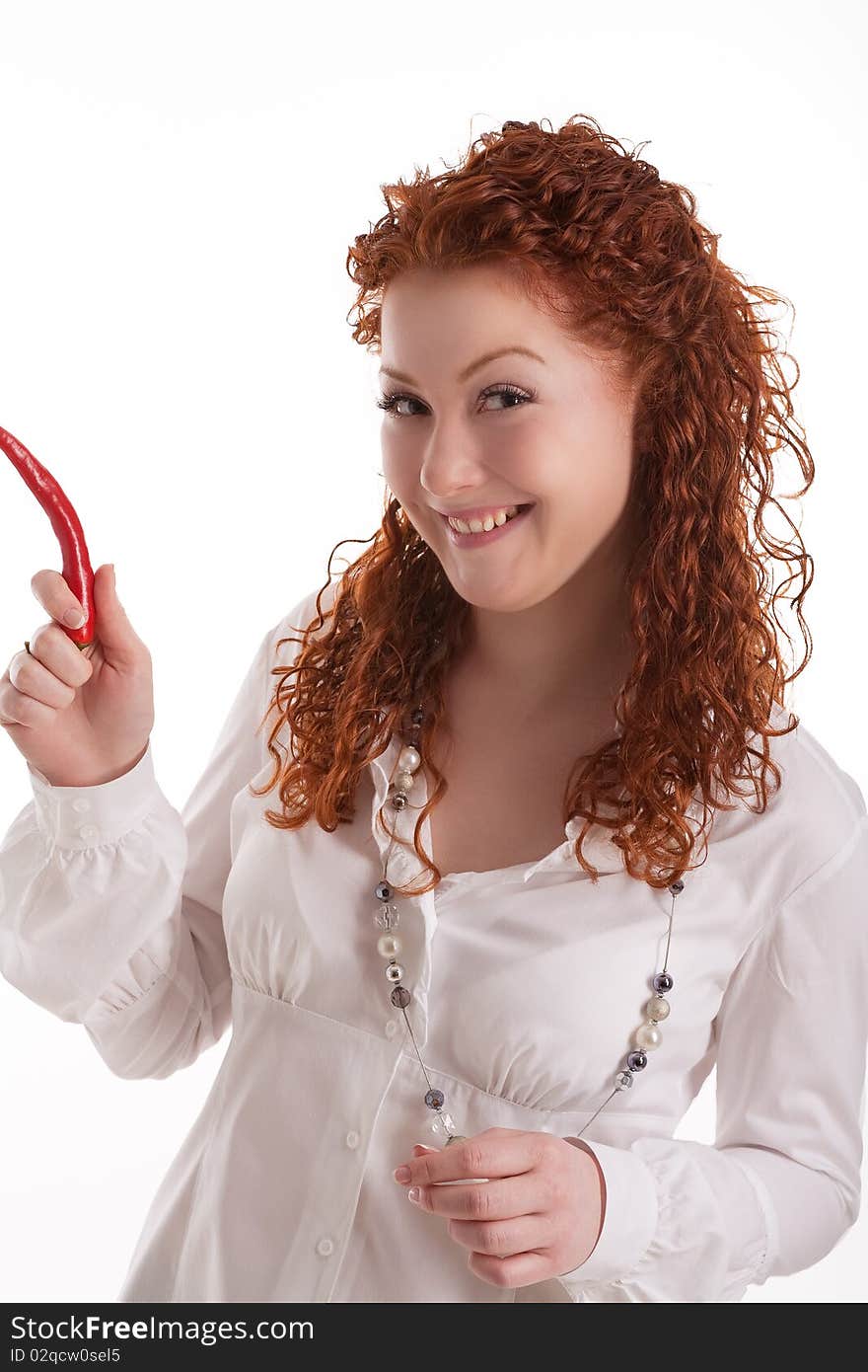 Cute and beautiful young caucasian girl with natural red hair demonstrating shocking chilly red pepper with positive facial expression standing isolated on white. Cute and beautiful young caucasian girl with natural red hair demonstrating shocking chilly red pepper with positive facial expression standing isolated on white