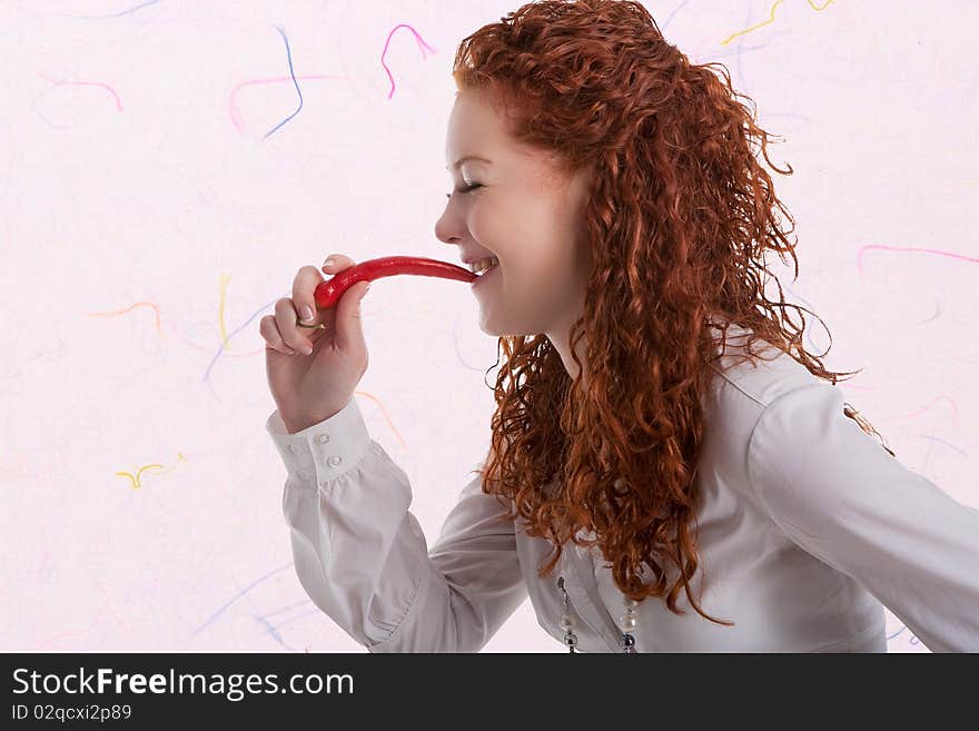 Red haired caucasian girl bitng red chilly pepper and having fun with standing in white shirt over textile background. Red haired caucasian girl bitng red chilly pepper and having fun with standing in white shirt over textile background