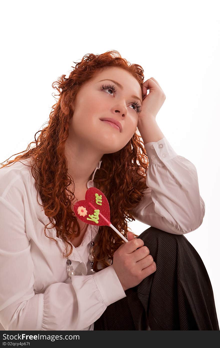 Cute and happy young caucasian girl with candy dreaming with relaxing facial expression sitting isolated on white. Cute and happy young caucasian girl with candy dreaming with relaxing facial expression sitting isolated on white