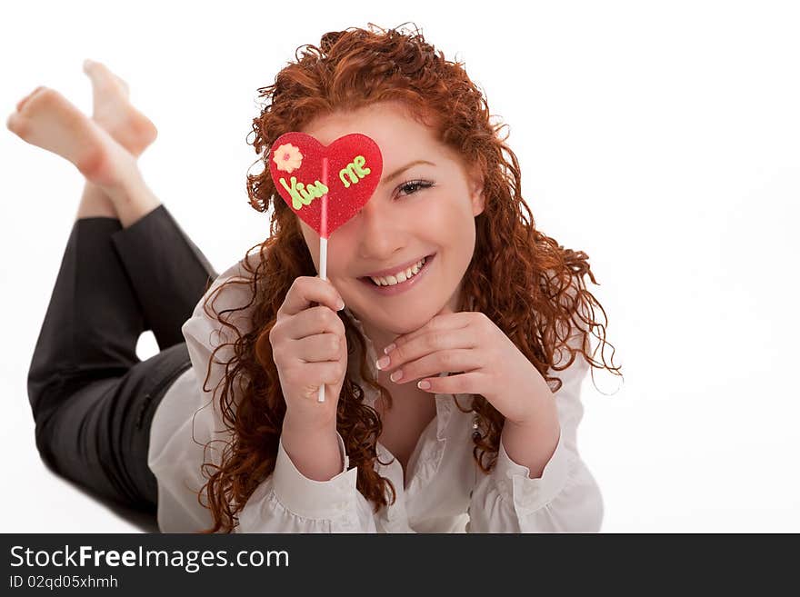 Happy laughing young red haired girl with heart-looking candy lying and relaxing with natural beautiful smile isolated over white. Happy laughing young red haired girl with heart-looking candy lying and relaxing with natural beautiful smile isolated over white