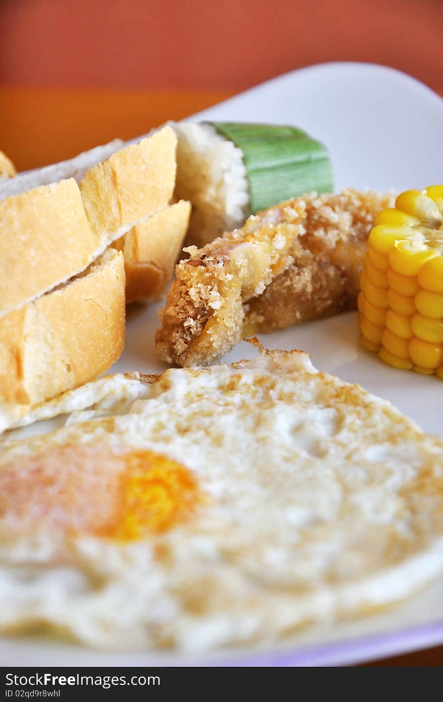 Breakfast food in dish, bread, rice roll, meat and fried egg.