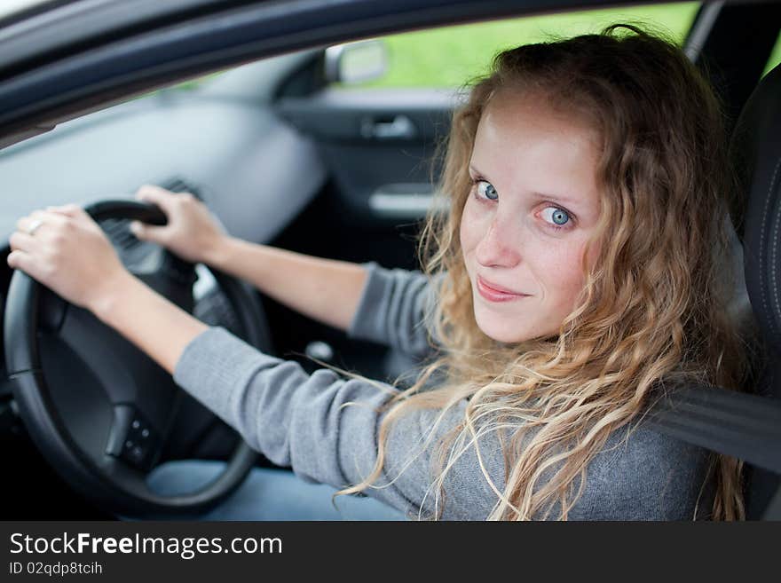 Pretty young woman driving her new car