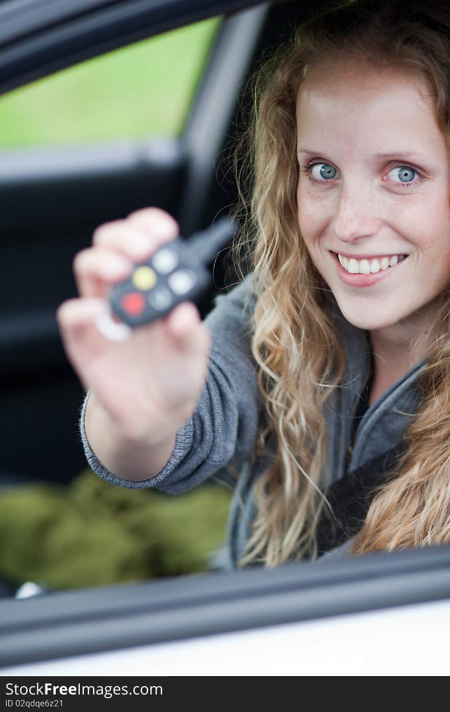 Pretty young woman showing off her brand new car - showing you the car keys. Pretty young woman showing off her brand new car - showing you the car keys