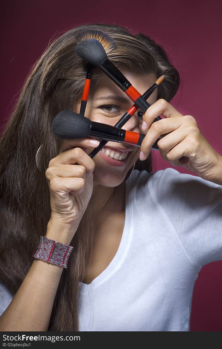 Young brunette smiling makeup artist with brushes and cosmetics