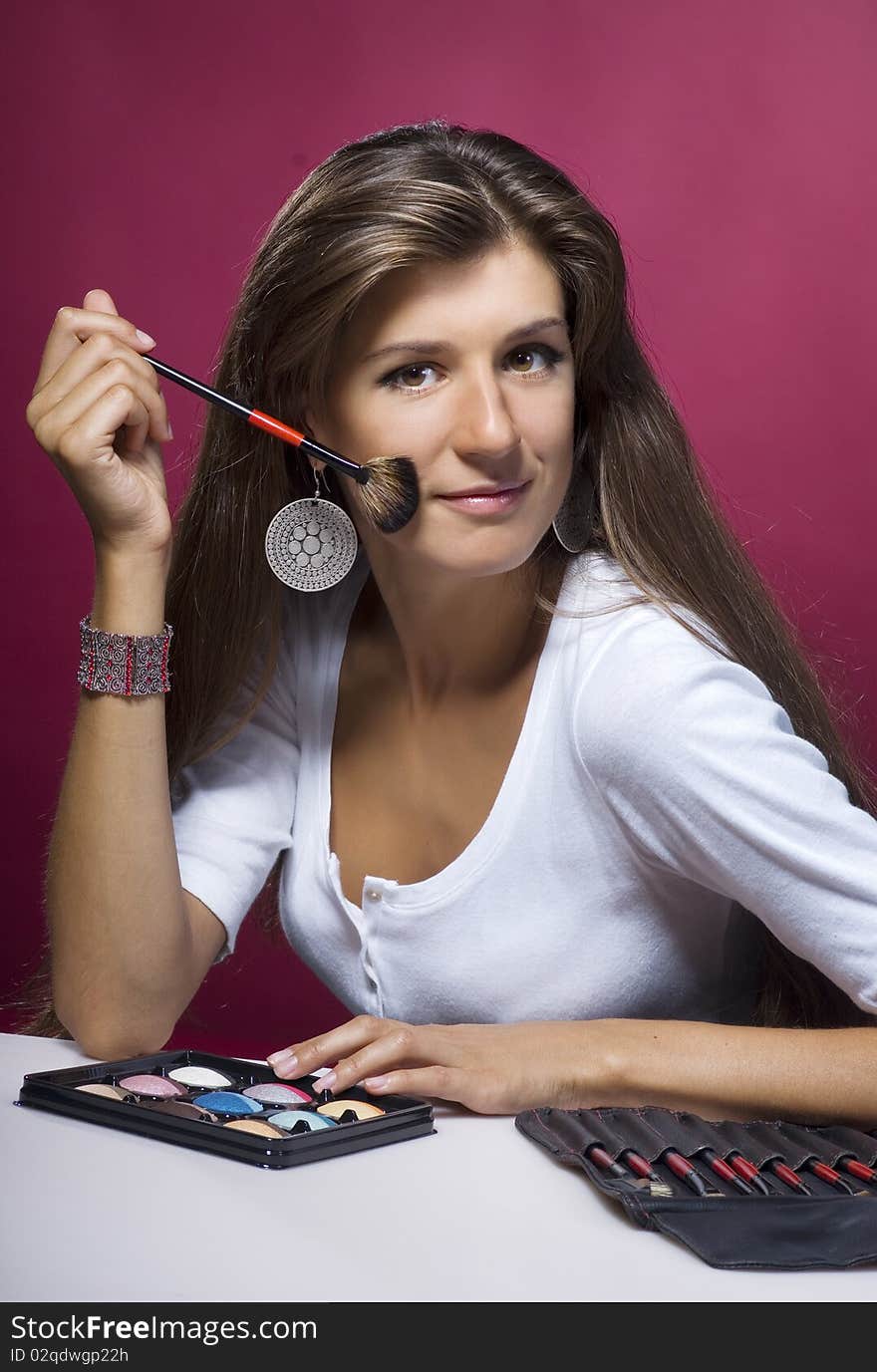 Young brunette makeup artist with brushes and cosmetics. Young brunette makeup artist with brushes and cosmetics