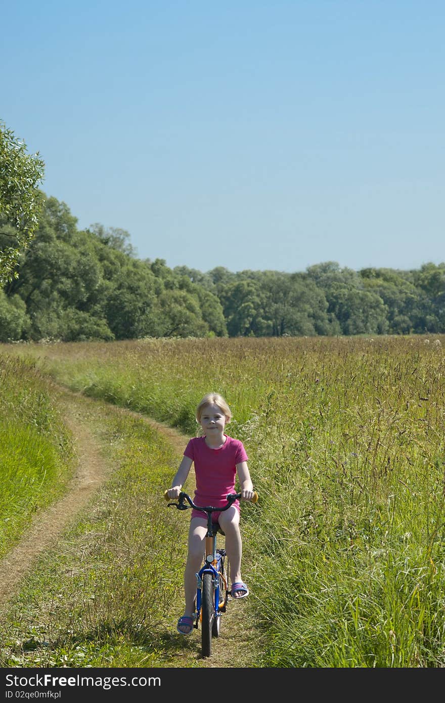 Little Girl On Bicycle On Meadow