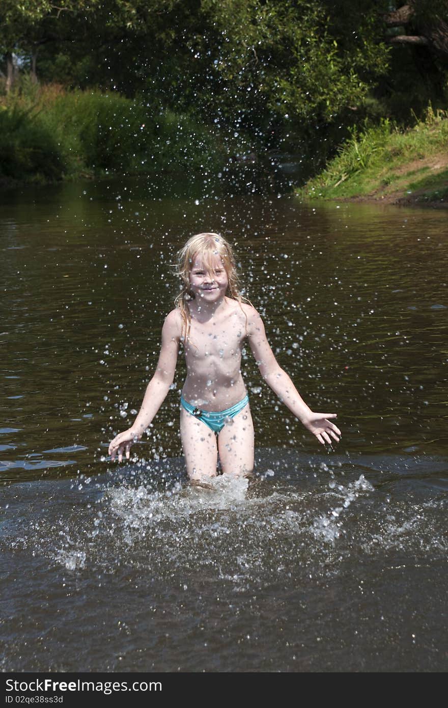 Little girl splashes with water in river