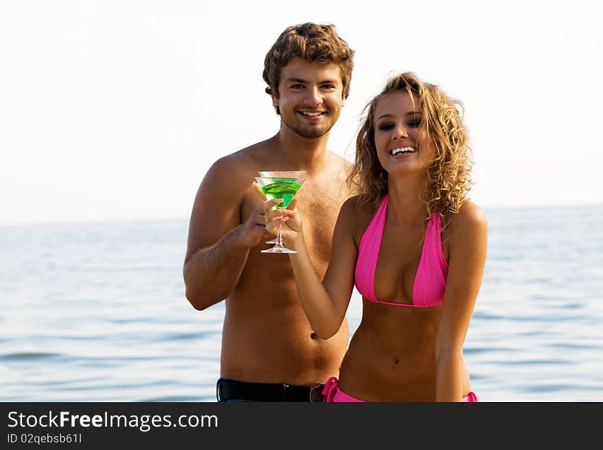 Young cheerful couple on the seaside with cocktails. Young cheerful couple on the seaside with cocktails