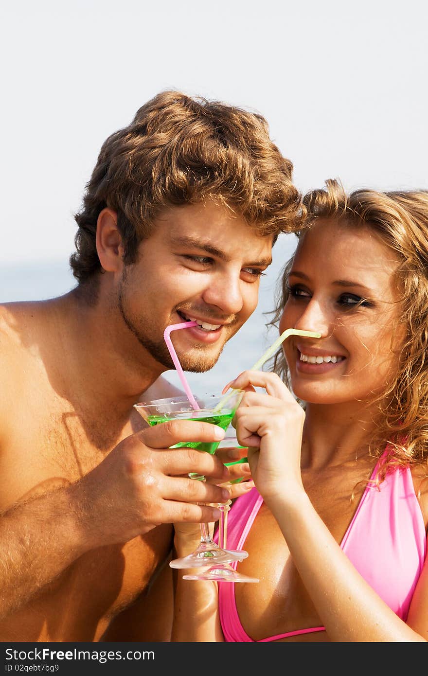 Young cheerful couple on the seaside with cocktails. Young cheerful couple on the seaside with cocktails