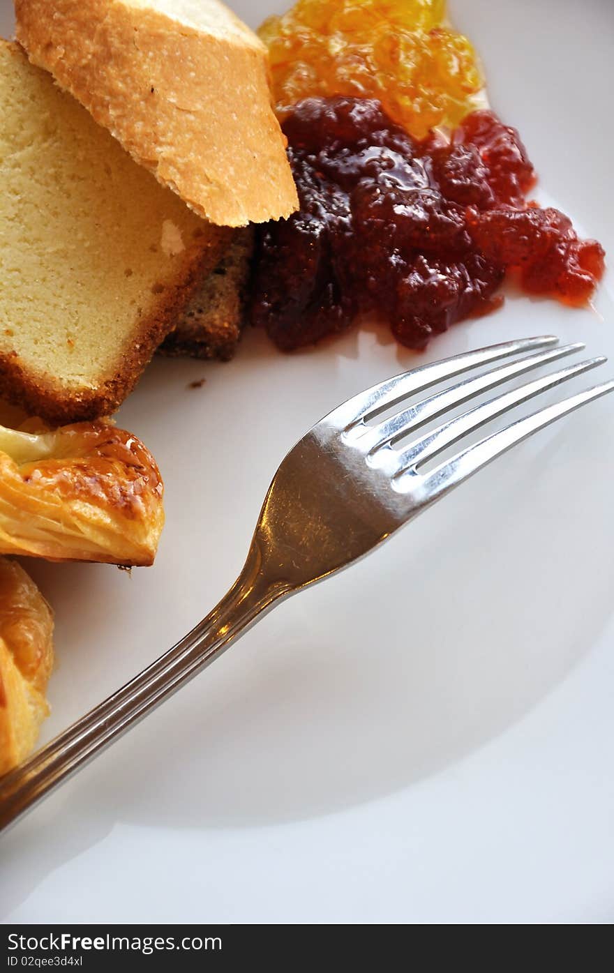 Bread and jam as breakfast, with a fork in plate.