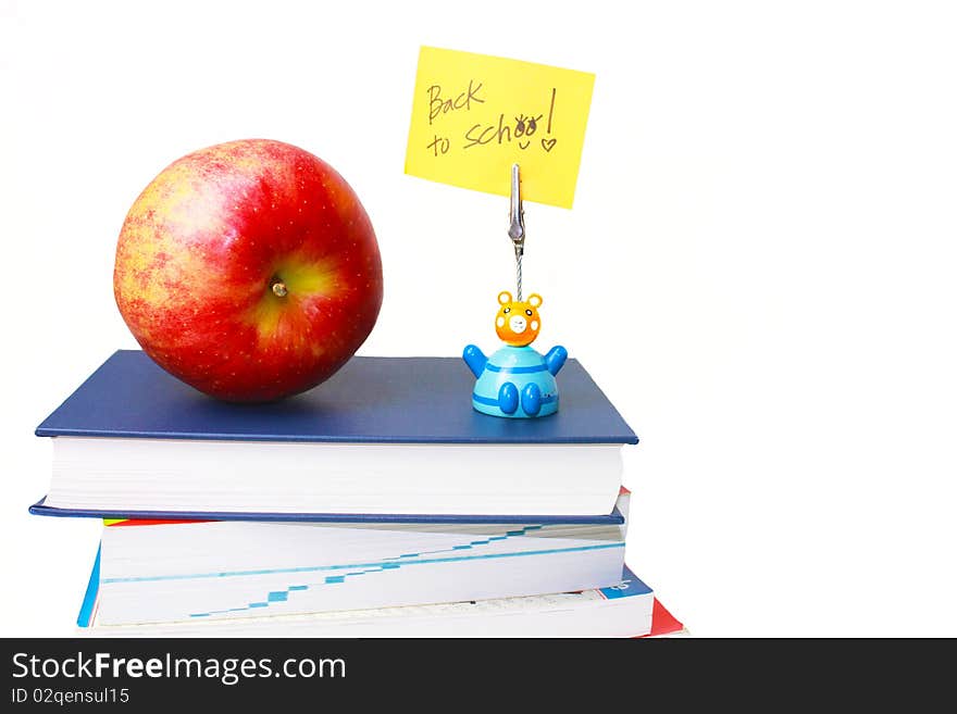 Frontal shot of 4 books with one apple a message holder with a note in white isolation. Frontal shot of 4 books with one apple a message holder with a note in white isolation.