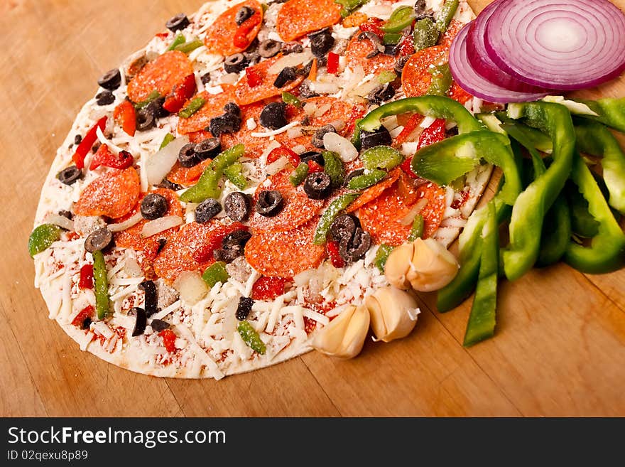 Raw pizza with vegetables and pepperoni