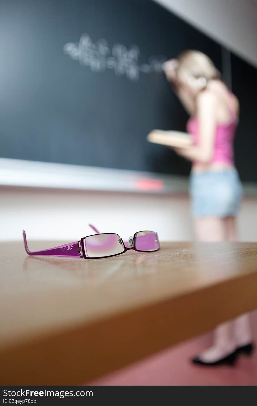 Pretty young college student writing on the chalkboard/blackboard during a math class