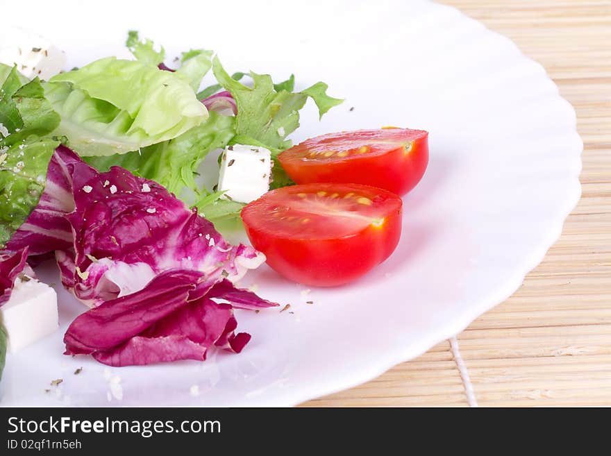 Salad with green and red leafs,tomato and sheep cheese on plate,closed-up. Salad with green and red leafs,tomato and sheep cheese on plate,closed-up