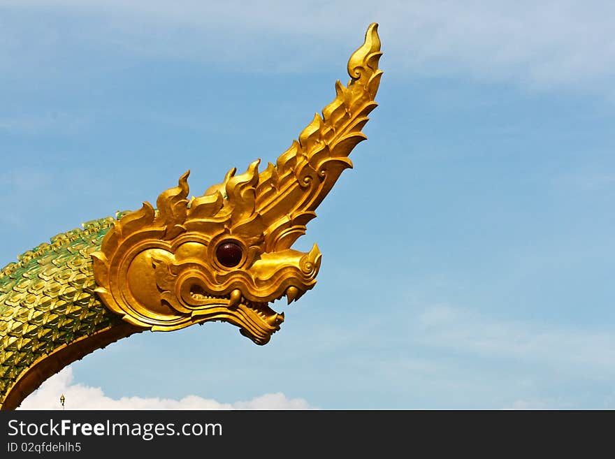 Golden Naga or dragon head statue is flying over on the blue sky. Golden Naga or dragon head statue is flying over on the blue sky