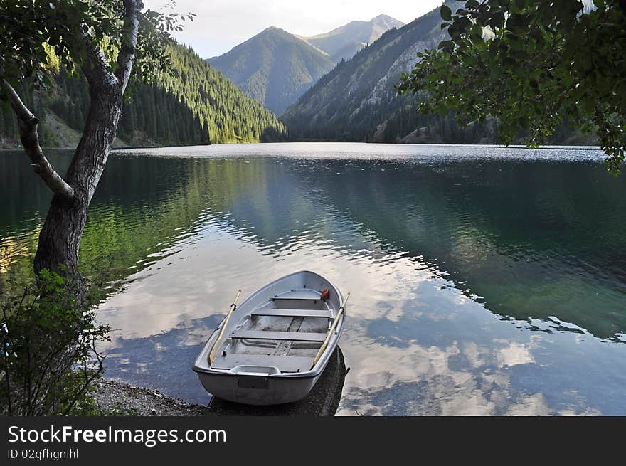 White rowing boat towed on Kolsai lake in tien shan mountains kazakhstan. White rowing boat towed on Kolsai lake in tien shan mountains kazakhstan