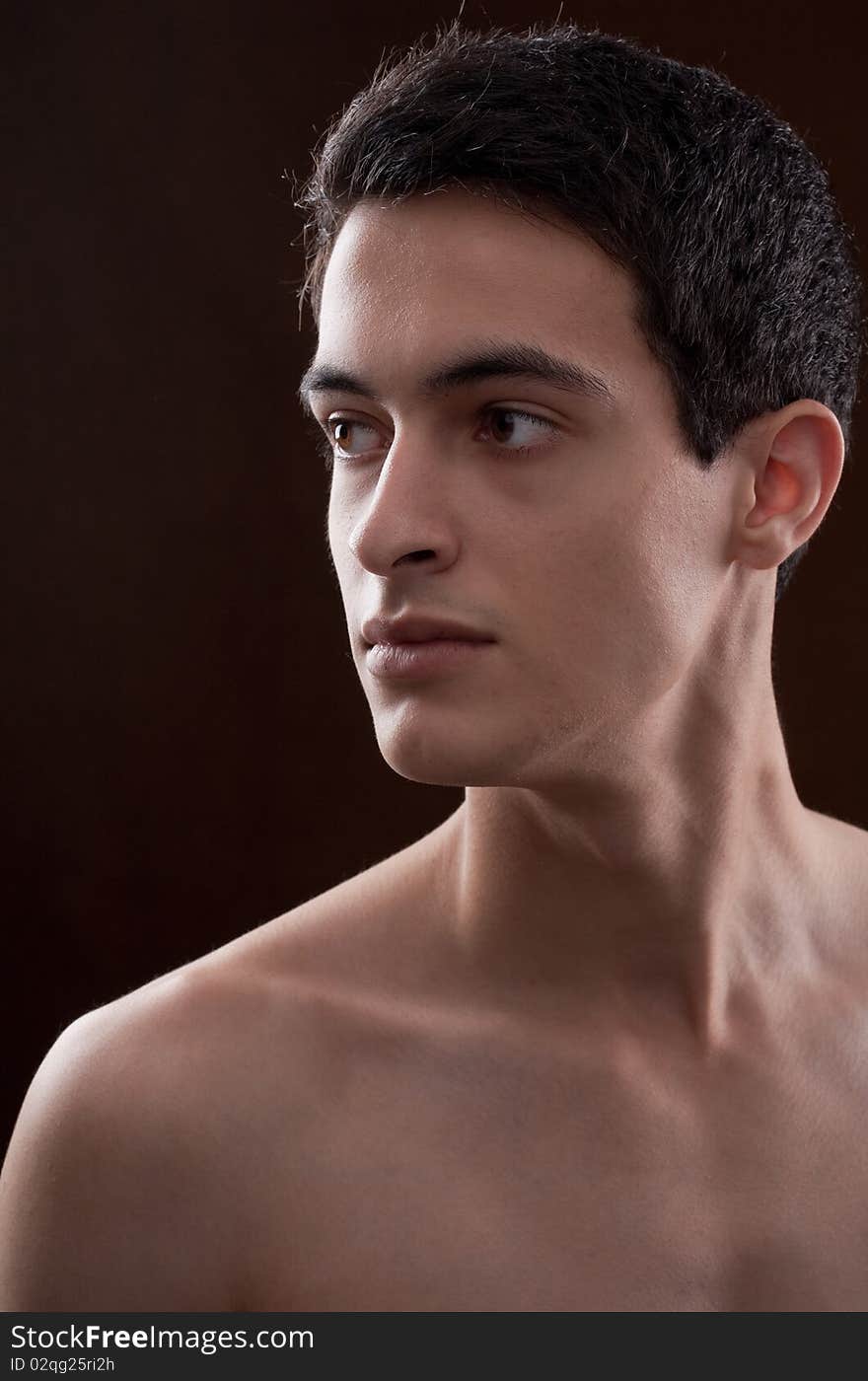 A fairly close up portrait of a young man against a dark background looking off to the side intensely. A fairly close up portrait of a young man against a dark background looking off to the side intensely