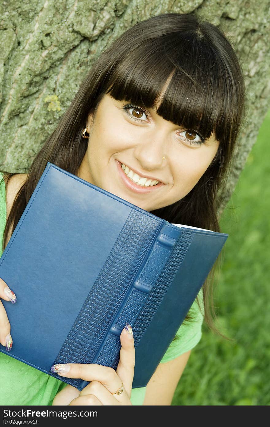 Young beautiful woman in a park with a notebook. Young beautiful woman in a park with a notebook.